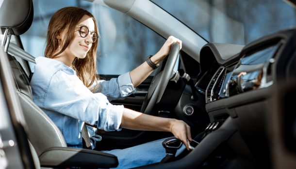 Young woman taking a smart phone from the place of wireless charging in the modern car in the city
